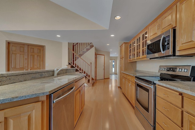 kitchen featuring light hardwood / wood-style floors, stainless steel appliances, light stone countertops, and sink