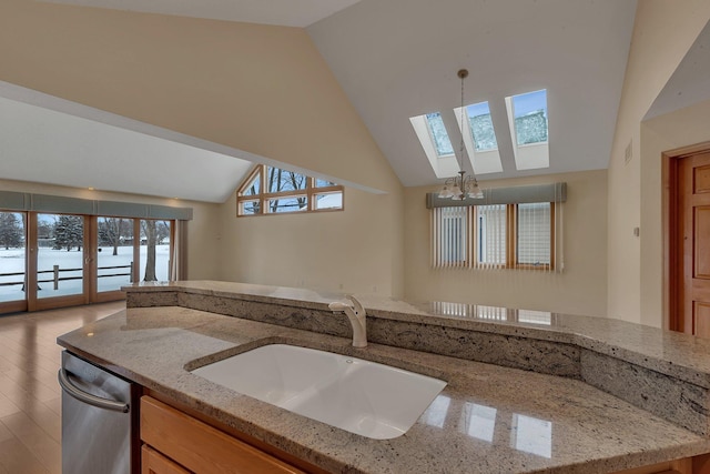 kitchen featuring sink, decorative light fixtures, light stone countertops, and dishwasher