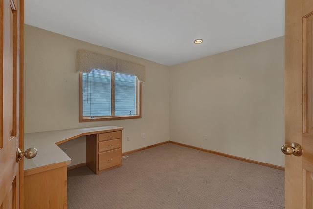 unfurnished office featuring light colored carpet and built in desk