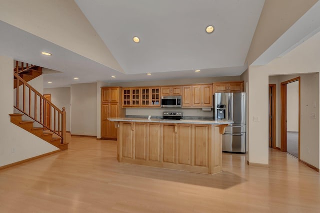 kitchen with lofted ceiling, light hardwood / wood-style flooring, stainless steel appliances, and a center island