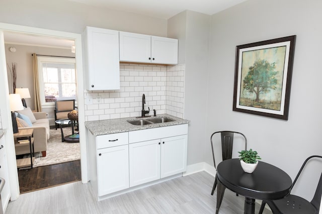 kitchen featuring tasteful backsplash, white cabinetry, sink, and light wood-type flooring