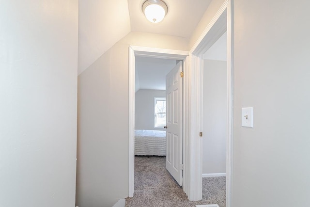 hallway with vaulted ceiling and light colored carpet