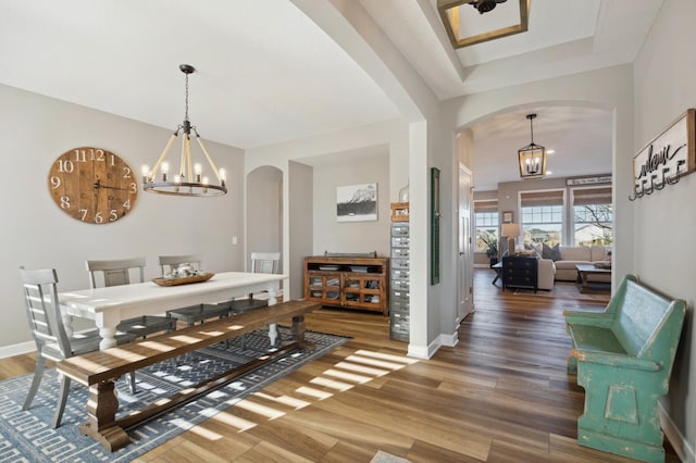 dining area with hardwood / wood-style floors and an inviting chandelier