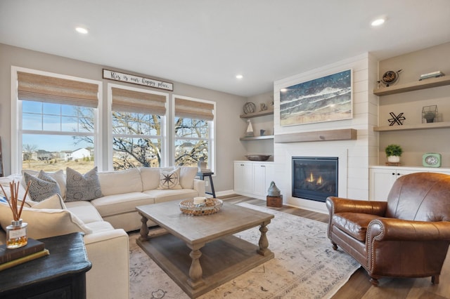 living room featuring a large fireplace, a wealth of natural light, and light hardwood / wood-style floors