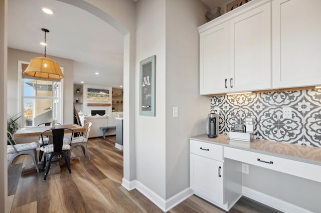 interior space featuring pendant lighting, backsplash, hardwood / wood-style flooring, and white cabinets