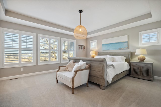 bedroom with a raised ceiling and light colored carpet