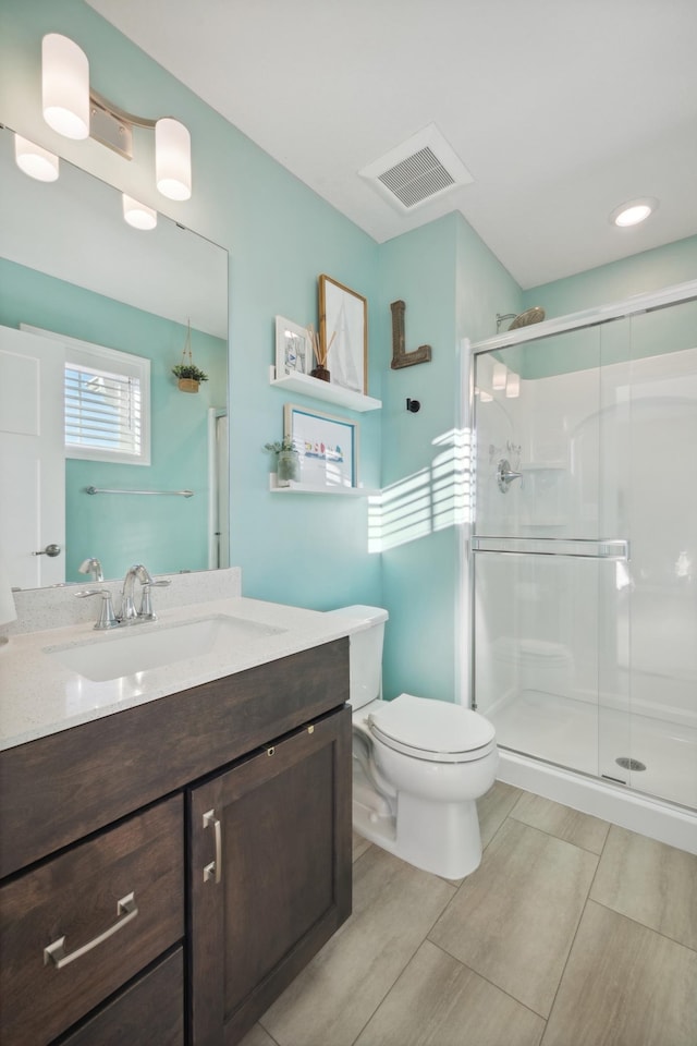 bathroom featuring vanity, a shower with door, and toilet