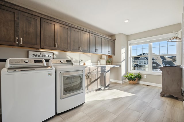 clothes washing area featuring cabinets, washing machine and dryer, and sink