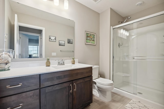 bathroom featuring vanity, toilet, and a shower with door