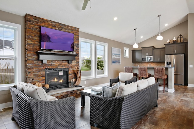 living room with ceiling fan, high vaulted ceiling, and a fireplace