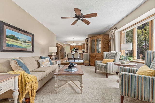 living room with a chandelier, light colored carpet, and ceiling fan