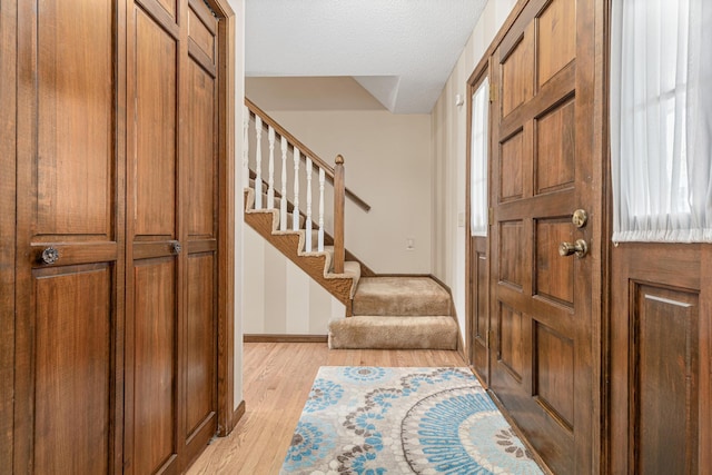 entryway with stairs, light wood finished floors, and baseboards