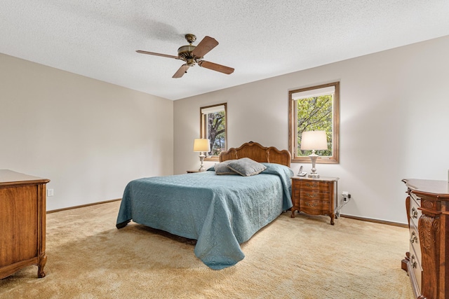 bedroom with light colored carpet, baseboards, a ceiling fan, and a textured ceiling