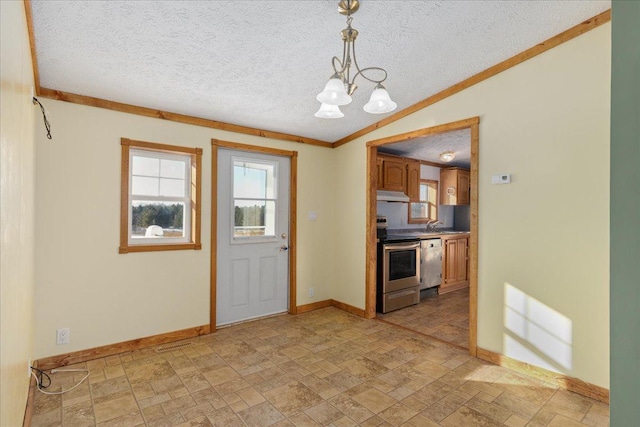 kitchen with crown molding, stainless steel appliances, a textured ceiling, decorative light fixtures, and vaulted ceiling