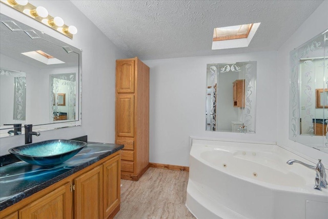 bathroom featuring wood-type flooring, a bathing tub, a skylight, and a textured ceiling