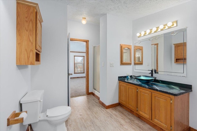 bathroom with hardwood / wood-style flooring, an enclosed shower, vanity, a textured ceiling, and toilet