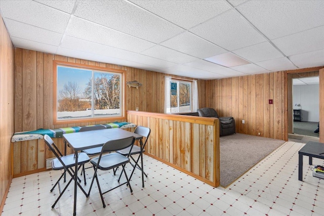 dining room with a paneled ceiling and wood walls