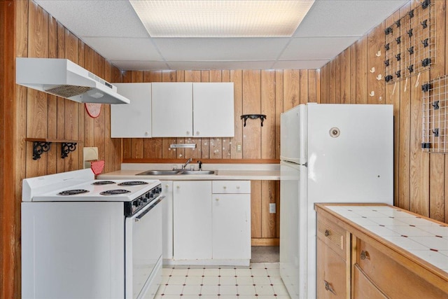 kitchen featuring white cabinetry, sink, white appliances, and wooden walls