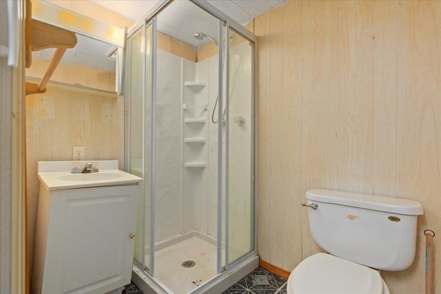 bathroom with toilet, vanity, wooden walls, and a shower with shower door