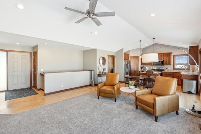 living room with ceiling fan, lofted ceiling, sink, and light wood-type flooring