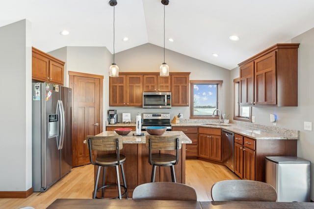 kitchen featuring sink, a center island, appliances with stainless steel finishes, pendant lighting, and light stone countertops