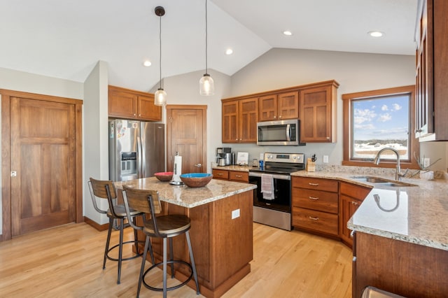 kitchen with sink, light stone counters, a center island, hanging light fixtures, and stainless steel appliances