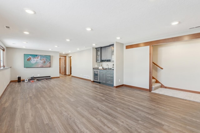 basement featuring hardwood / wood-style flooring, beverage cooler, indoor wet bar, and a textured ceiling