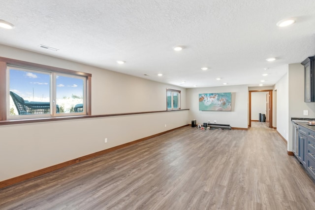 unfurnished living room with a wealth of natural light, hardwood / wood-style floors, and a textured ceiling