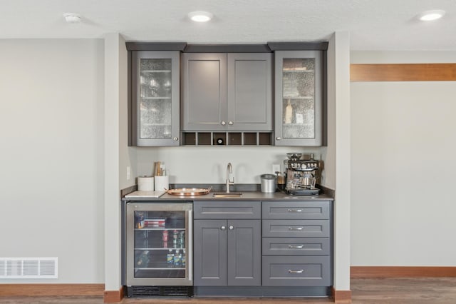 bar featuring dark hardwood / wood-style floors, beverage cooler, sink, and gray cabinetry