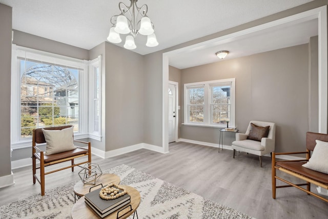 sitting room with light wood finished floors, baseboards, and a chandelier