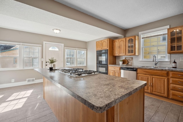 kitchen with a kitchen island, a sink, visible vents, light wood-style floors, and appliances with stainless steel finishes