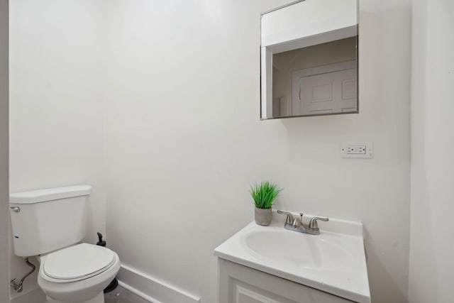 half bath featuring vanity, toilet, and baseboards