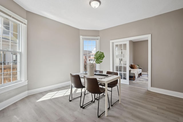 dining area featuring light wood-style flooring, baseboards, and french doors