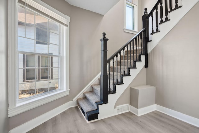 stairway with a wealth of natural light, baseboards, and wood finished floors