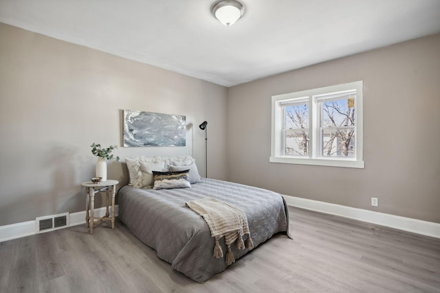 bedroom with light wood finished floors, visible vents, and baseboards