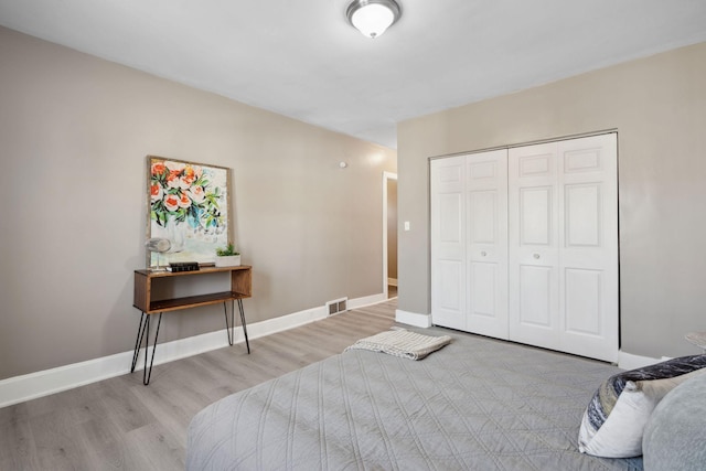 bedroom with light wood-style floors, a closet, visible vents, and baseboards