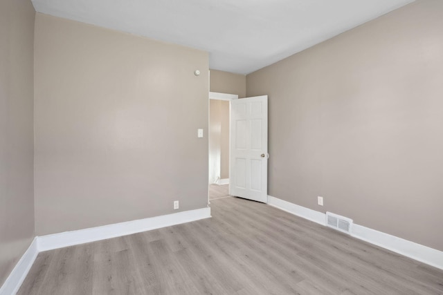 empty room featuring visible vents, light wood-style flooring, and baseboards