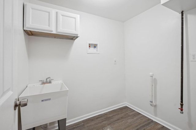 clothes washing area with washer hookup, dark wood finished floors, cabinet space, a sink, and baseboards