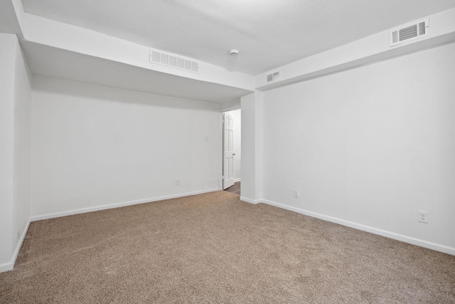 spare room with carpet flooring, visible vents, and baseboards