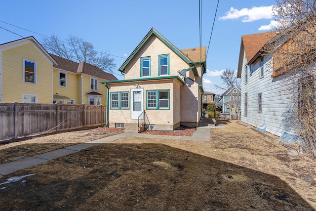 back of property with entry steps, fence, and stucco siding