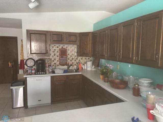 kitchen featuring lofted ceiling, sink, decorative backsplash, light tile patterned floors, and white dishwasher