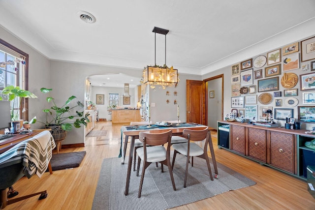 dining space with a wealth of natural light, a notable chandelier, and light hardwood / wood-style flooring