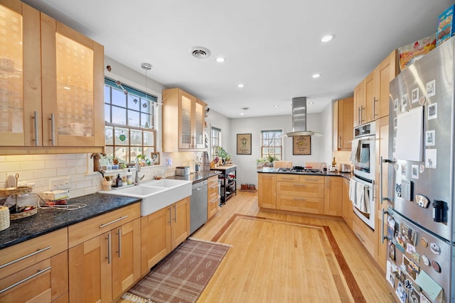 kitchen featuring appliances with stainless steel finishes, pendant lighting, sink, island exhaust hood, and light hardwood / wood-style flooring