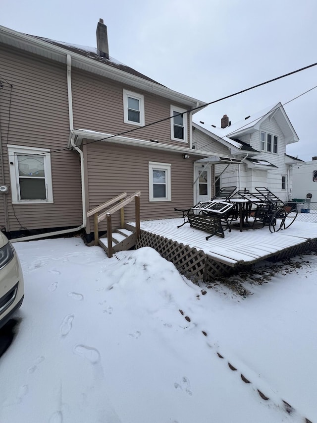 snow covered rear of property featuring a deck