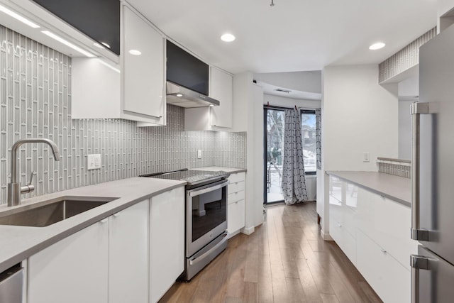 kitchen with sink, appliances with stainless steel finishes, backsplash, dark hardwood / wood-style floors, and white cabinets