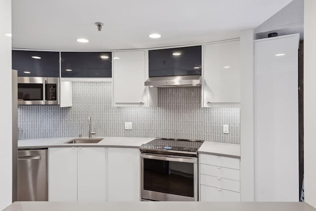 kitchen with stainless steel appliances, white cabinetry, sink, and backsplash