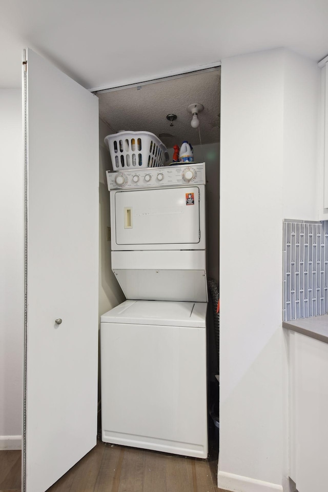 washroom with dark hardwood / wood-style flooring and stacked washer / drying machine