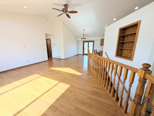 interior space featuring light wood-type flooring, visible vents, an upstairs landing, built in features, and baseboards