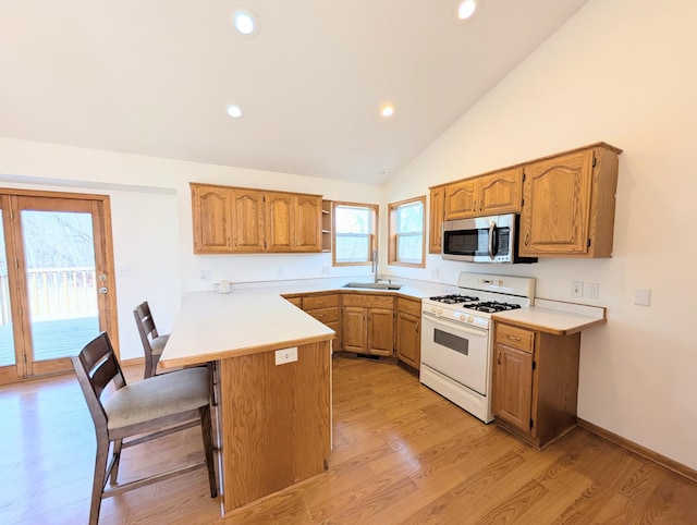 kitchen with a kitchen bar, a sink, stainless steel microwave, gas range gas stove, and a peninsula