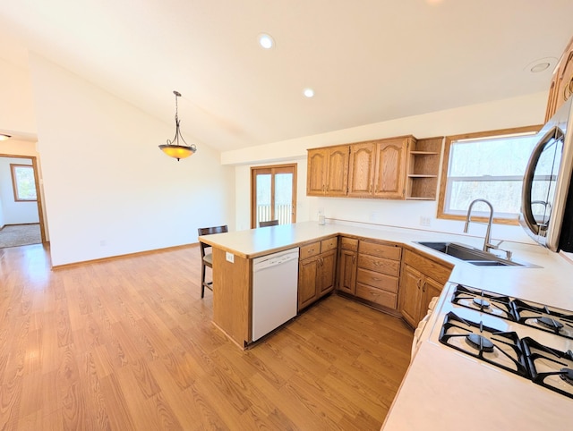 kitchen featuring a sink, light wood finished floors, lofted ceiling, dishwasher, and light countertops